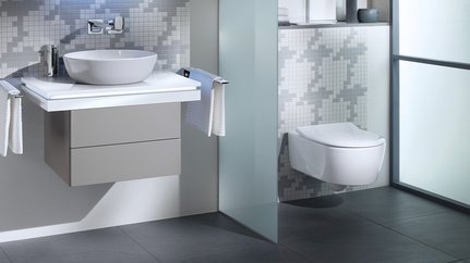Ein Waschbeckenunterschrank und eine Toilette mit einem Glas getrennt
