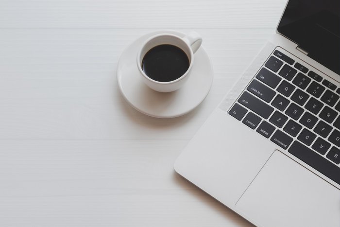 Ein Tisch auf dem eine Tasse Kaffe steht, und ein Laptop liegt